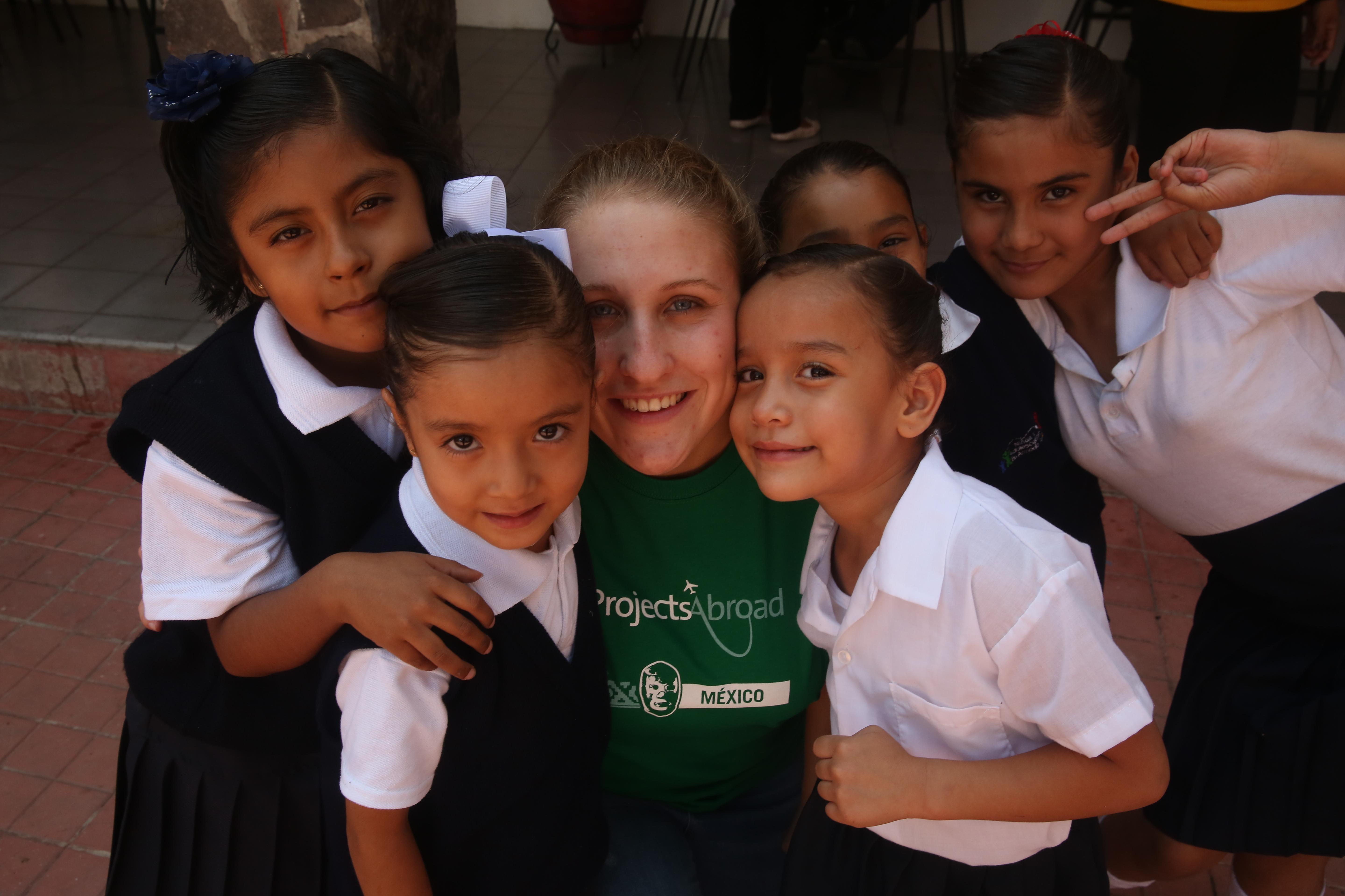A group photo of a Teaching volunteer and her students outside one of our volunteer teaching placements in Mexico Projects Abroad volunteer teaching in Mexico poses with her students